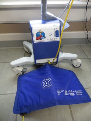 A blue bag is on the floor next to an oxygen concentrator.